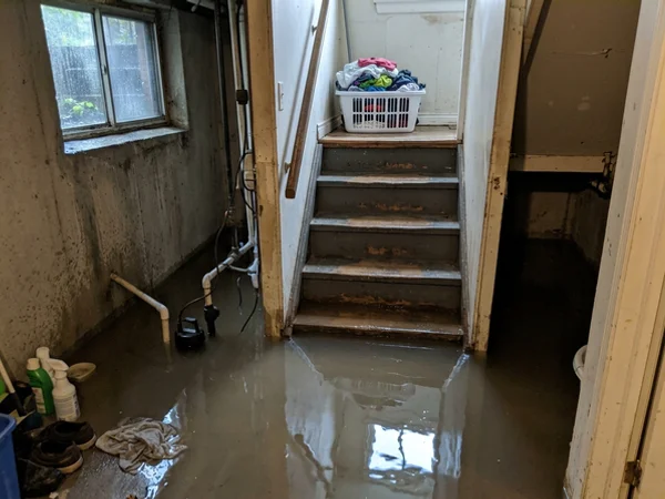 Flooded basement stairwell at night with an overflowing sump pit
